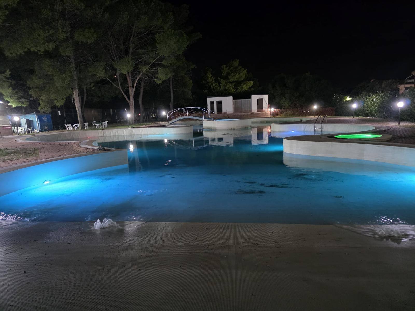 Piscina illuminata di sera con giochi d'acqua vicino a Casa Vacanza Pinto